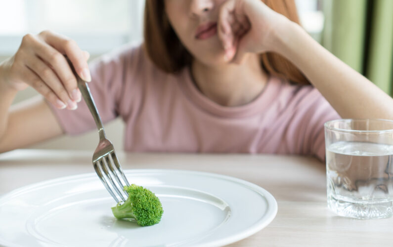Woman on dieting. Depressed teen looking at her empty plate dinner.